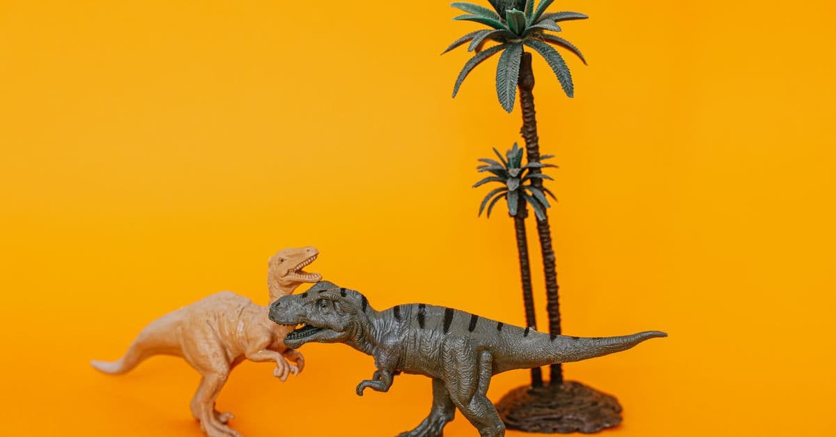Close-up of dinosaur figurines and palm trees on a vibrant orange backdrop.