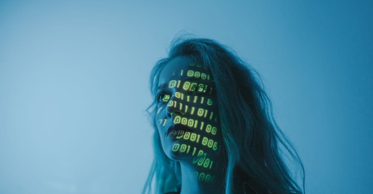 A woman with binary code lights projected on her face, symbolizing technology.