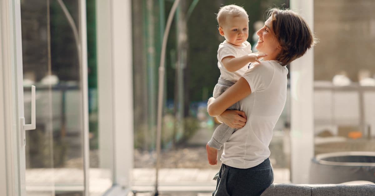 A joyful moment between mother and child in a sunlit room, capturing love and togetherness.