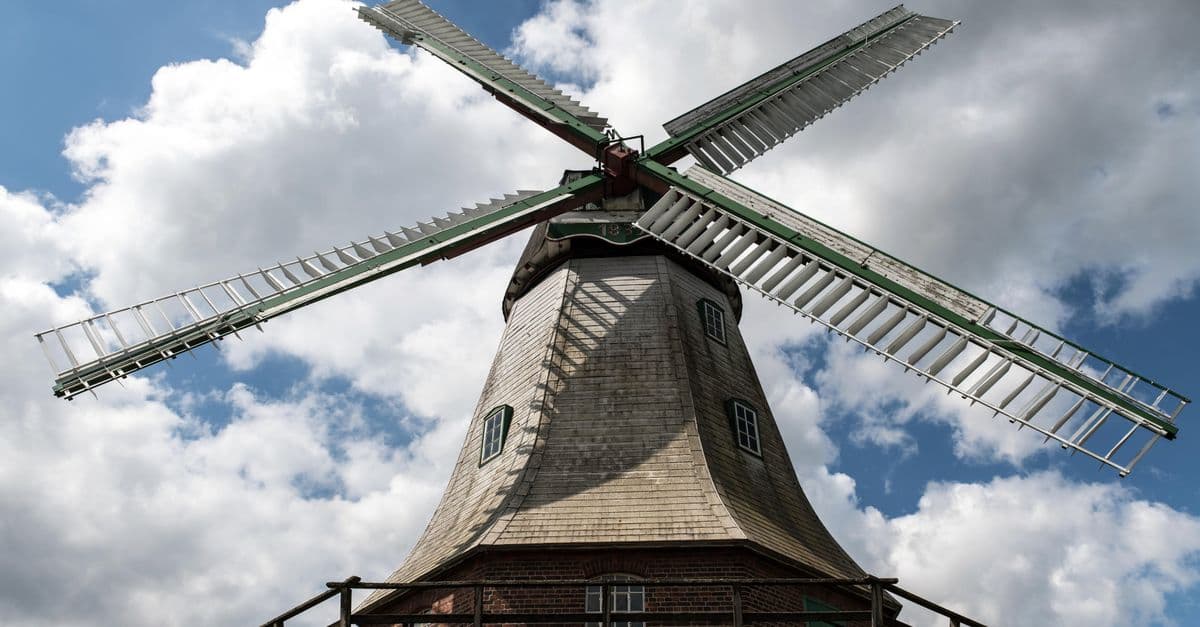 Traditional windmill under a blue sky with clouds in Artlenburg, Germany. Perfect for energy and nature themes.