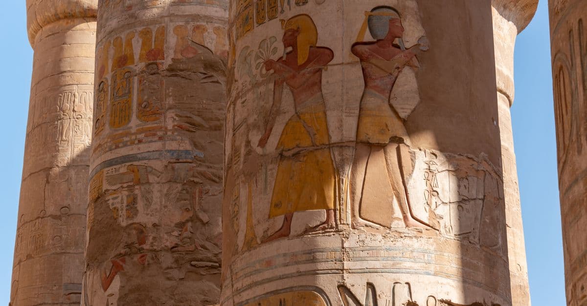 Close-up of hieroglyphs and figures on ancient Egyptian temple columns, showcasing rich historical art.