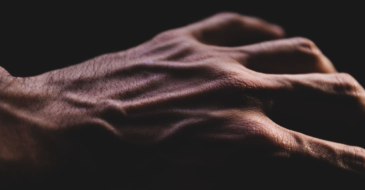 Detailed close-up of a veined adult hand with dramatic lighting and shadow effects.