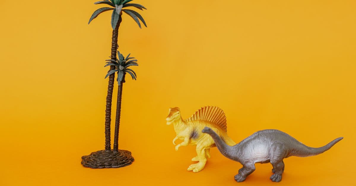 Colorful toy dinosaurs and palm trees on a vivid yellow backdrop, perfect for playful themes.