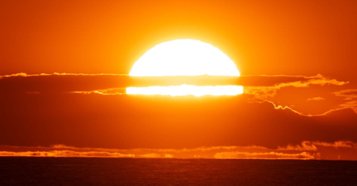 A breathtaking view of the sun setting over the ocean, casting a warm, fiery glow.