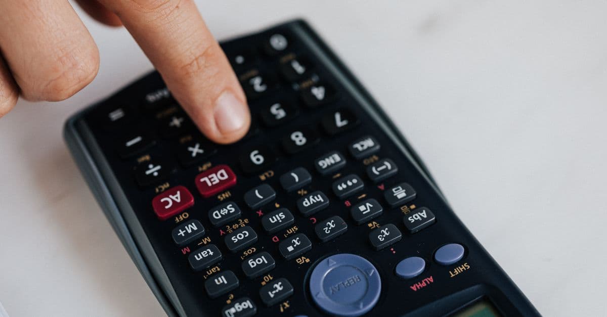 From above of crop anonymous economist calculating on calculator with plastic buttons while making budget on marble table