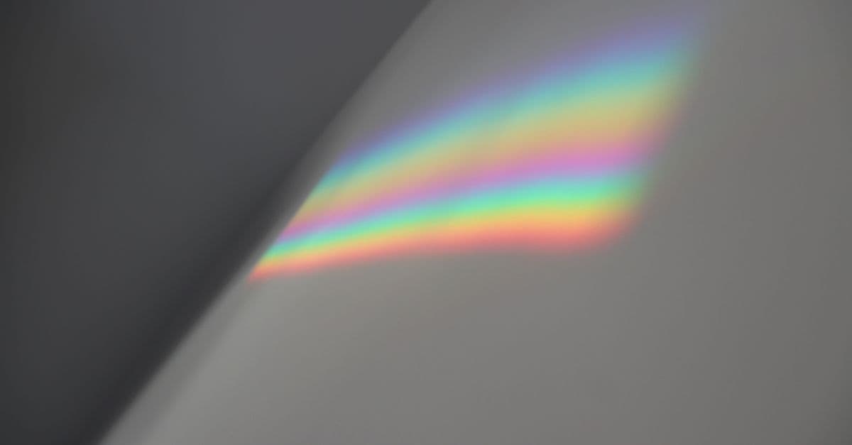 Soft rainbow light spectrum reflected on a neutral grey wall indoors.