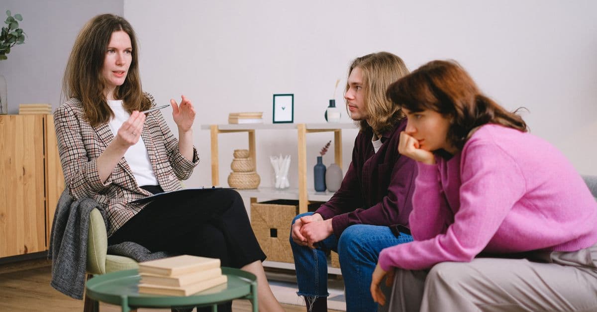 A counselor having a discussion with two students in an inviting, modern interior space.