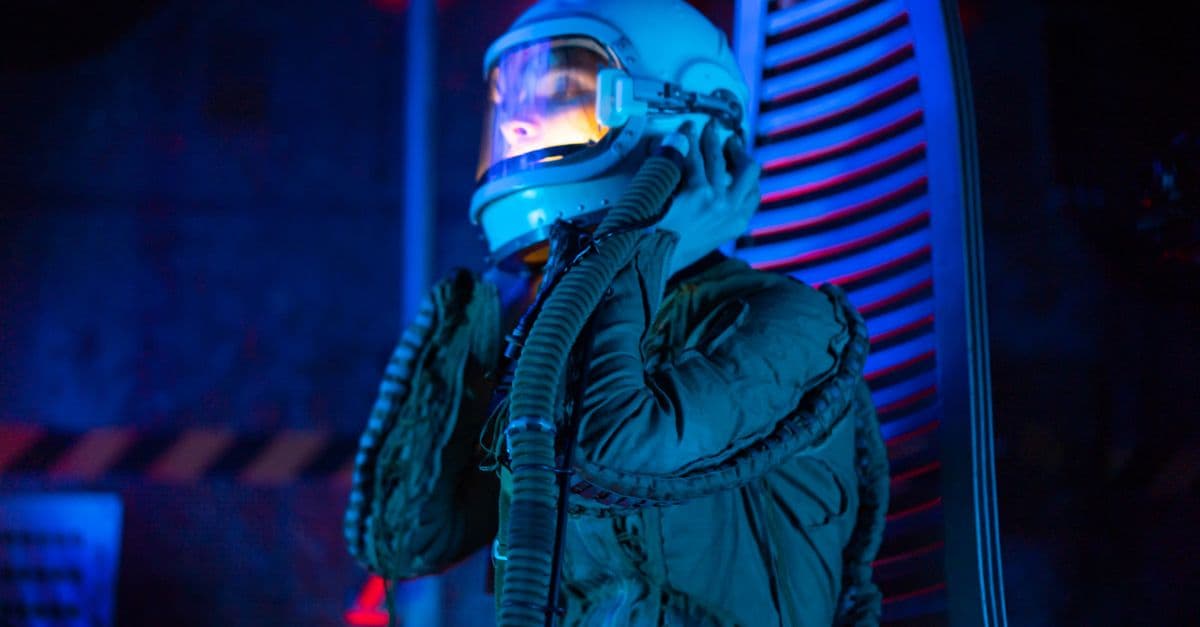 A person in a spacesuit explores a futuristic spaceship with blue lighting, conveying sci-fi atmosphere.