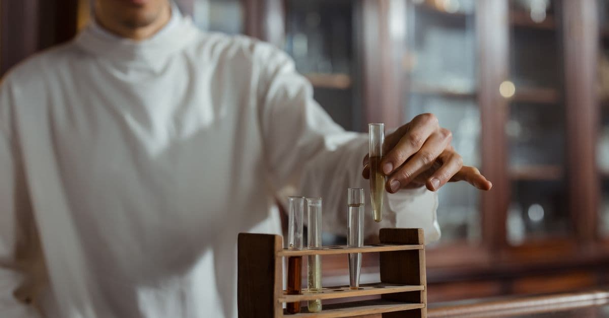Scientist in lab coat handling test tubes in a laboratory setting.