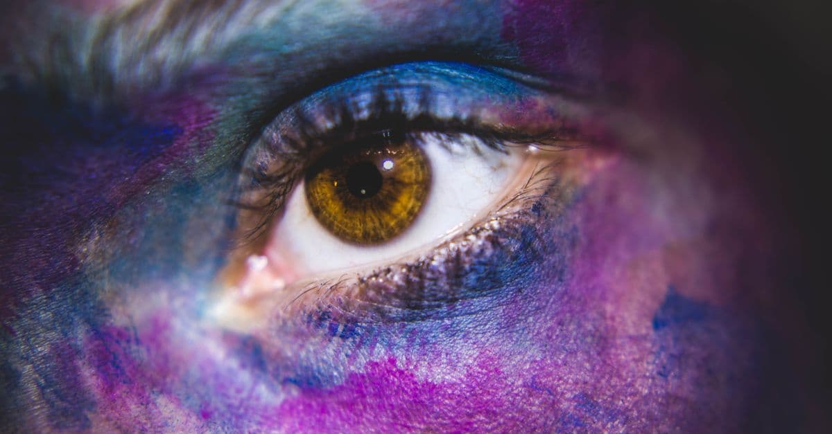 A vibrant close-up of a human eye surrounded by colorful paint, showcasing artistic expression.
