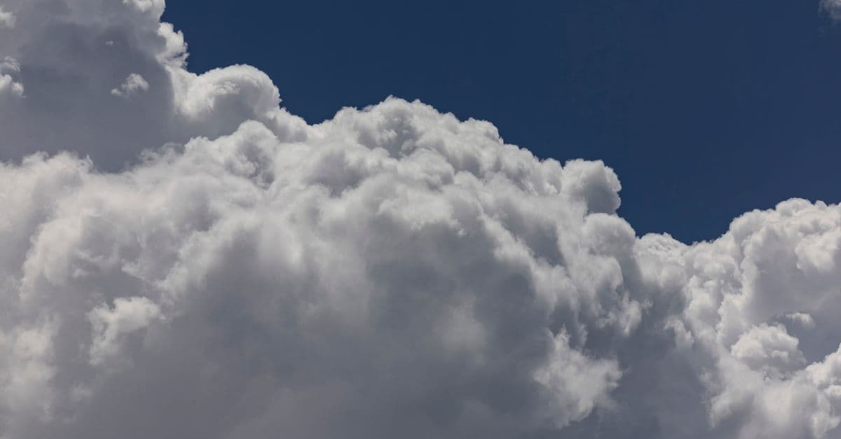 A vibrant image capturing dramatic fluffy clouds against a clear blue sky, ideal for weather themes.