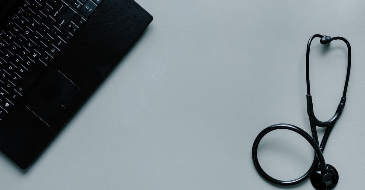 Minimalist image depicting a laptop and stethoscope representing telemedicine and digital health.