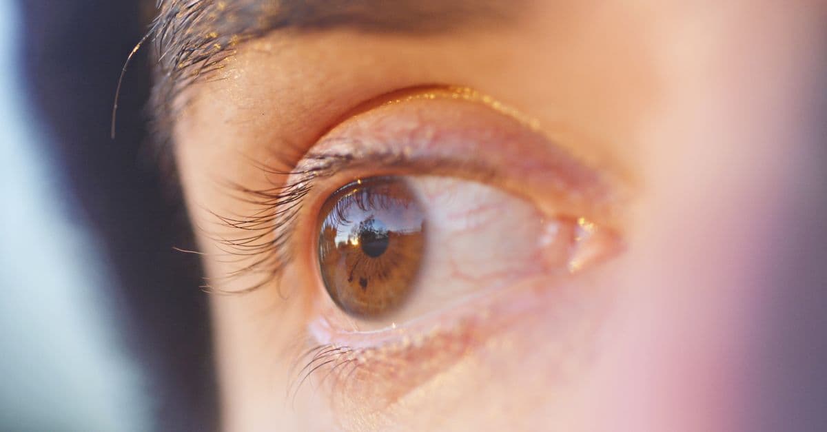 Macro shot of a human eye reflecting the environment, capturing the details of the iris and eyelashes.
