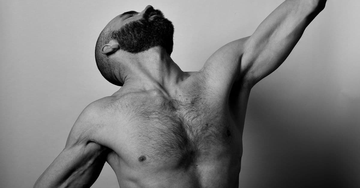Dramatic black and white portrait of a muscular man in a dynamic pose.