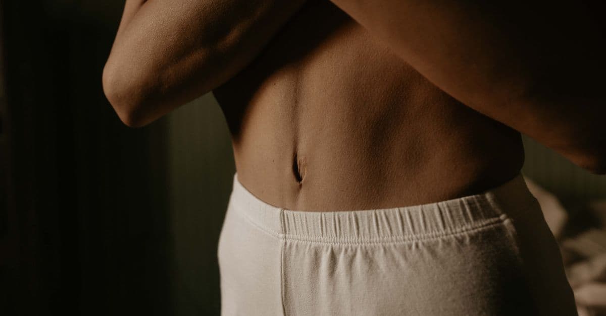 Artistic close-up of a person's torso in soft lighting, showcasing natural skin texture and detail.