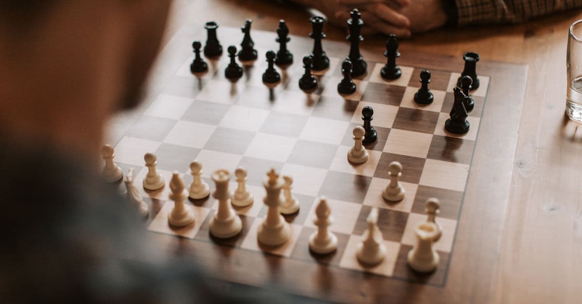 Chess players engaged in a strategic game on a wooden table, showcasing thought and strategy.