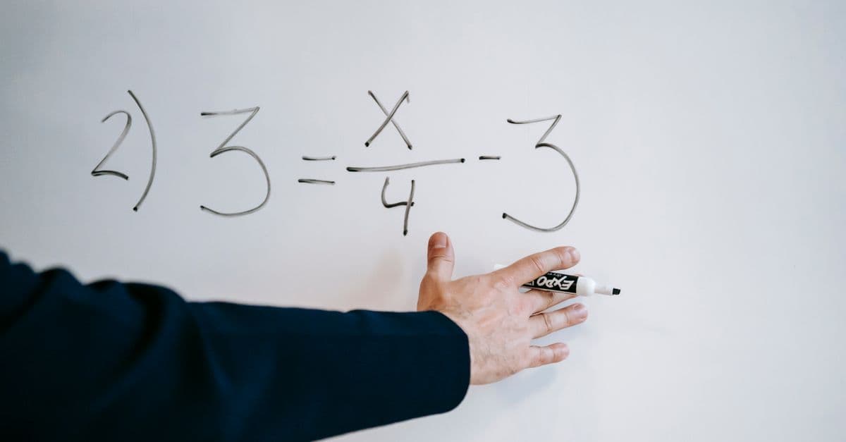 A hand writing a mathematical equation on a whiteboard with a marker.