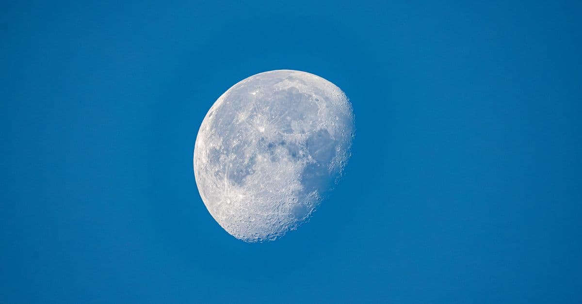 Detailed view of the moon's surface against a clear blue sky during daytime.