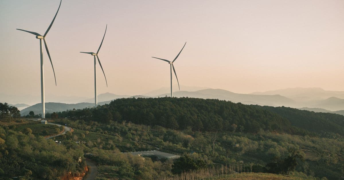 Wind turbines on a hilly rural landscape during dusk, promoting green energy.