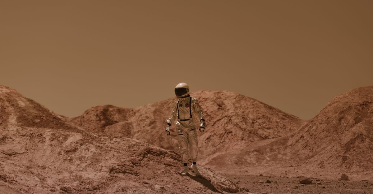 An astronaut in a spacesuit ventures across a barren, Mars-like desert landscape.