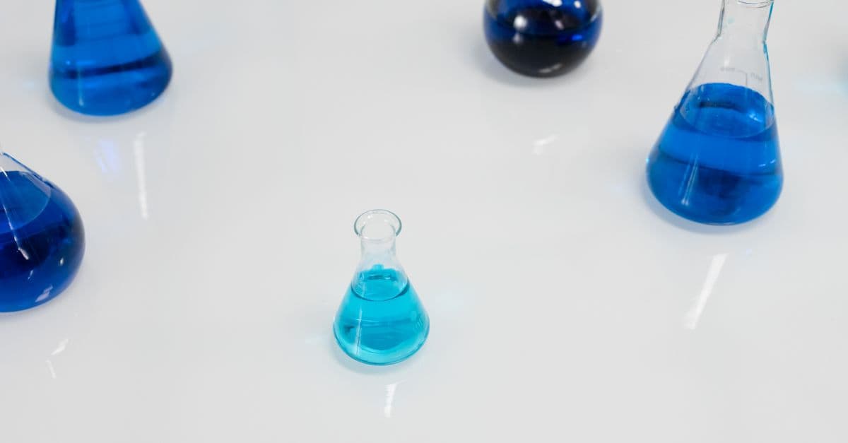 Various glass flasks filled with blue liquid in a scientific setting, perfect for research themes.