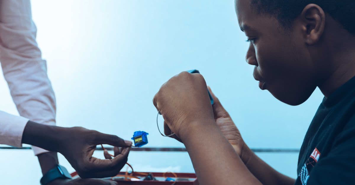 Two students work on a hands-on project, connecting components in a tech class.