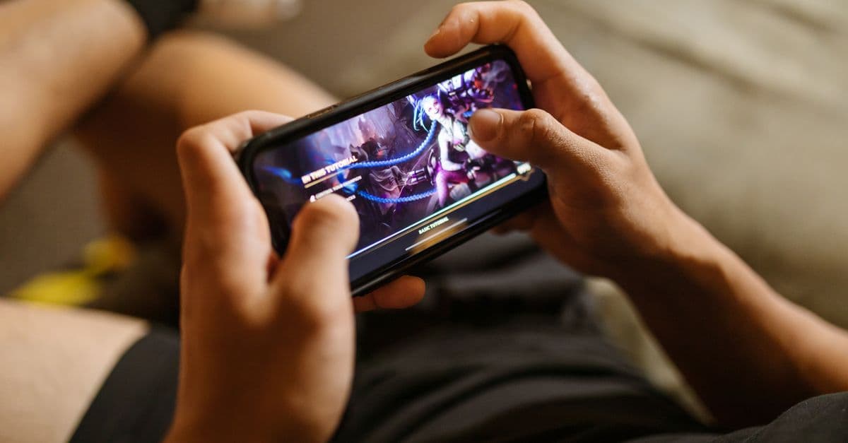 A person playing a mobile video game on a smartphone, focusing on gaming and technology lifestyle.