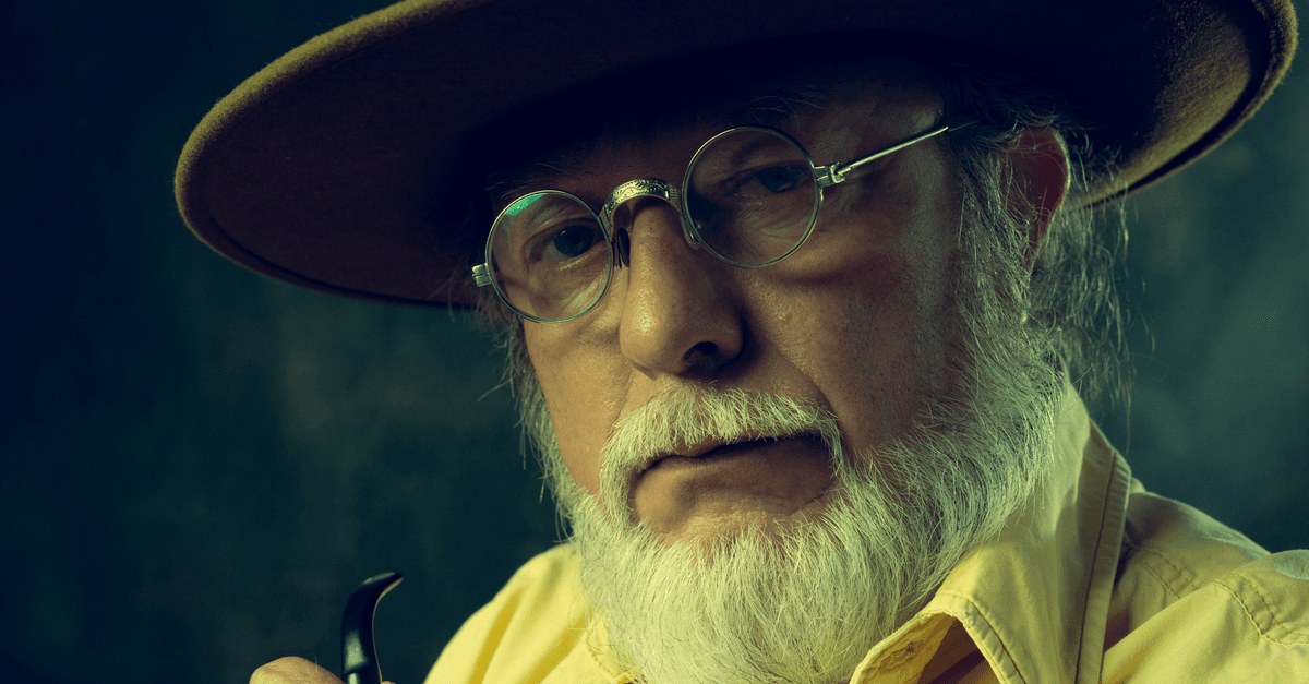 Close-up portrait of a senior man with a hat and pipe, showcasing wisdom and character.
