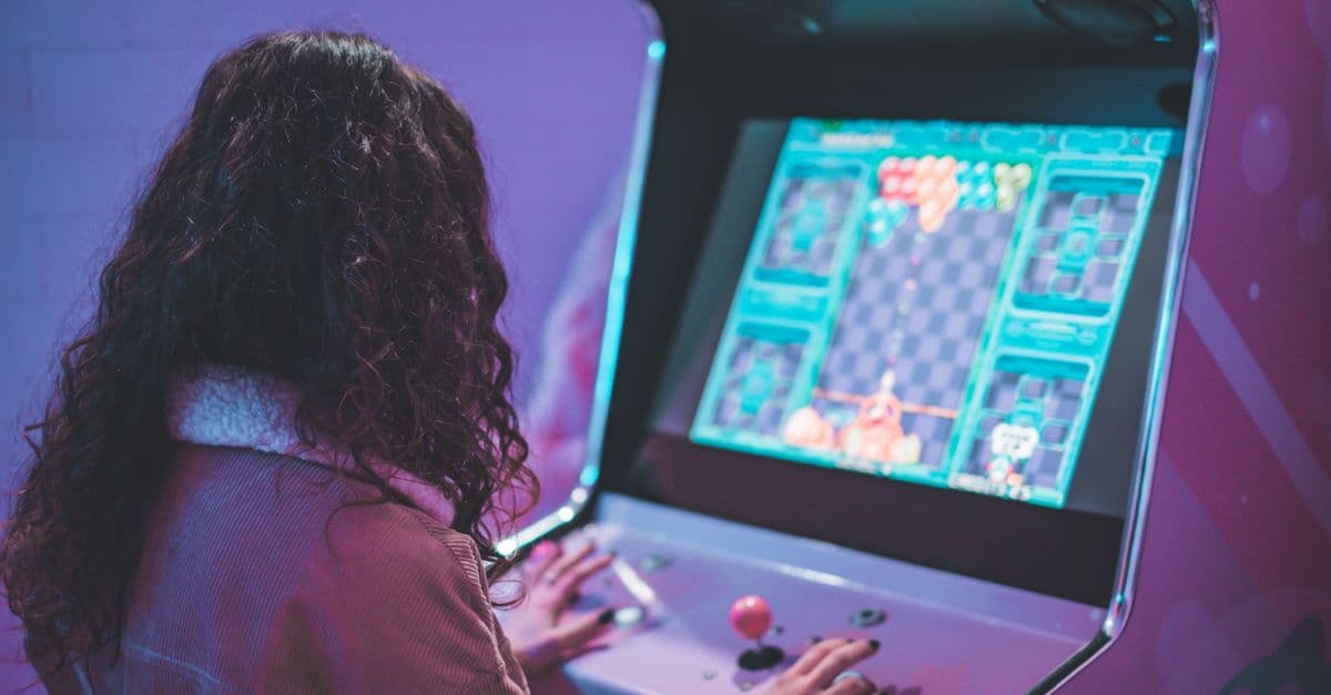 A woman enjoys a nostalgic moment playing a classic arcade machine indoors.