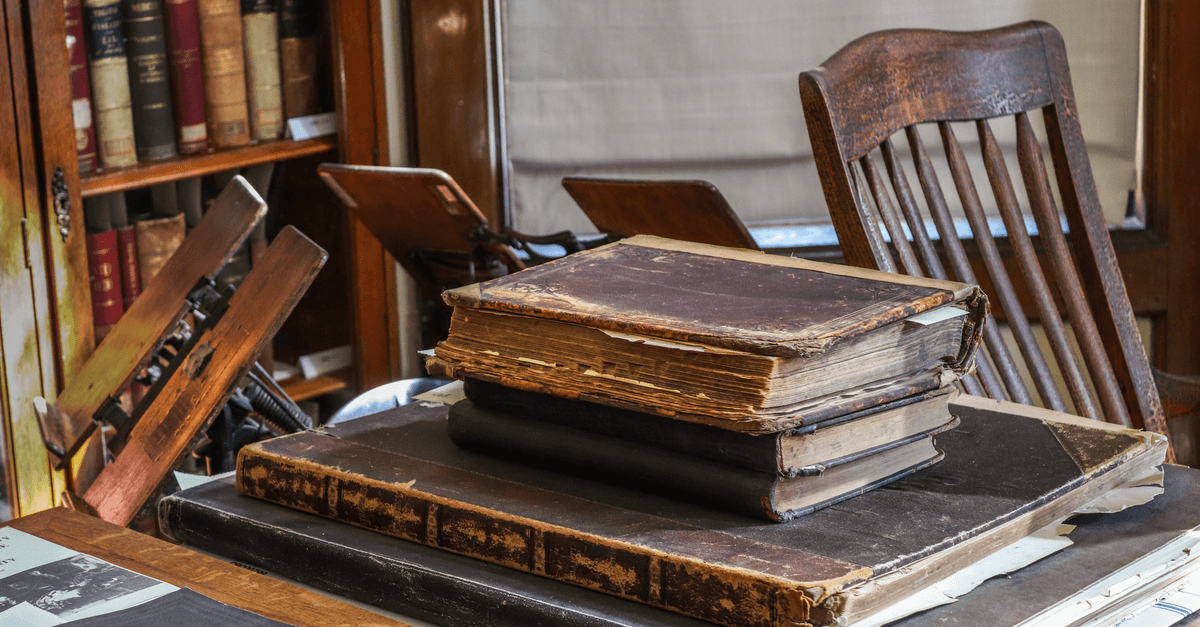 A collection of vintage books and classic wooden furniture in an antique library setting, highlighting history and literature.