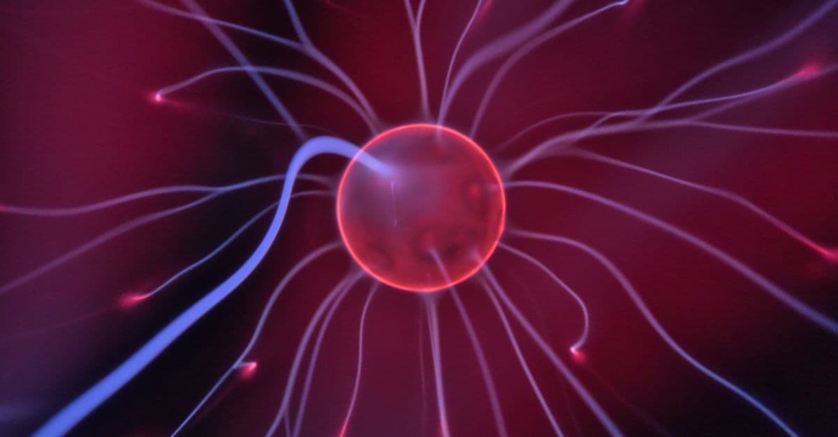 Close-up of a glowing plasma ball with colorful electric currents reaching outwards.