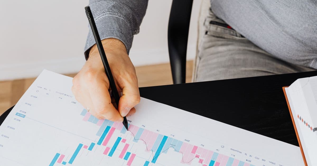 Detailed financial graph showing analysis by a person with a pen indoors.