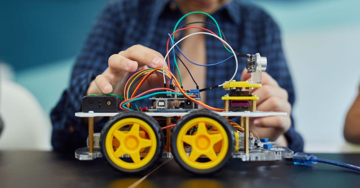 Child involved in building a small robot as part of a hands-on STEM education project, focusing on electronics.
