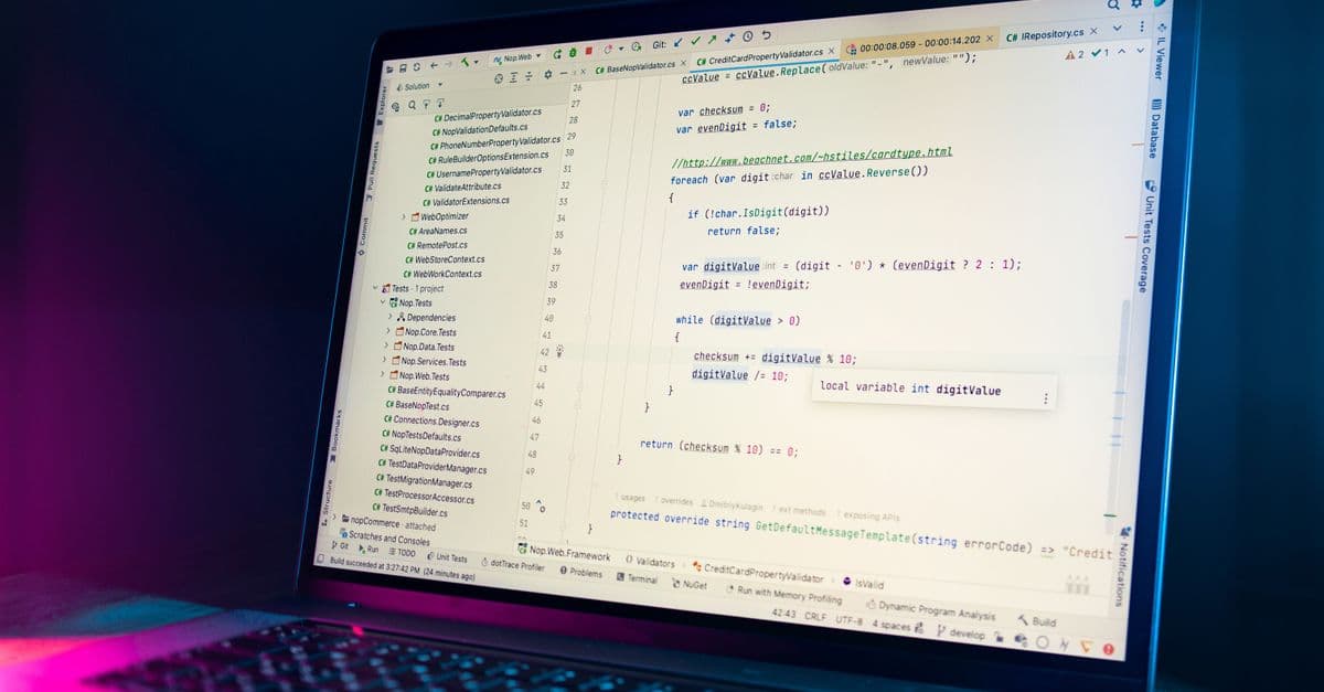 A laptop screen showing a code editor with visible programming code in a dimly lit environment.