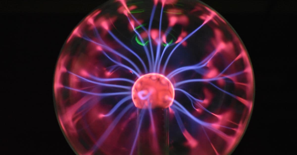 Close-up of a glowing plasma ball featuring colorful electric streaks against a dark background.