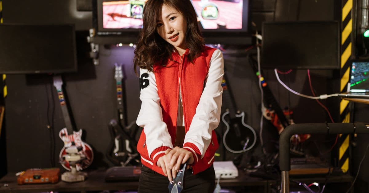Young woman enjoying Guitar Hero session in a vibrant gaming lounge setting.