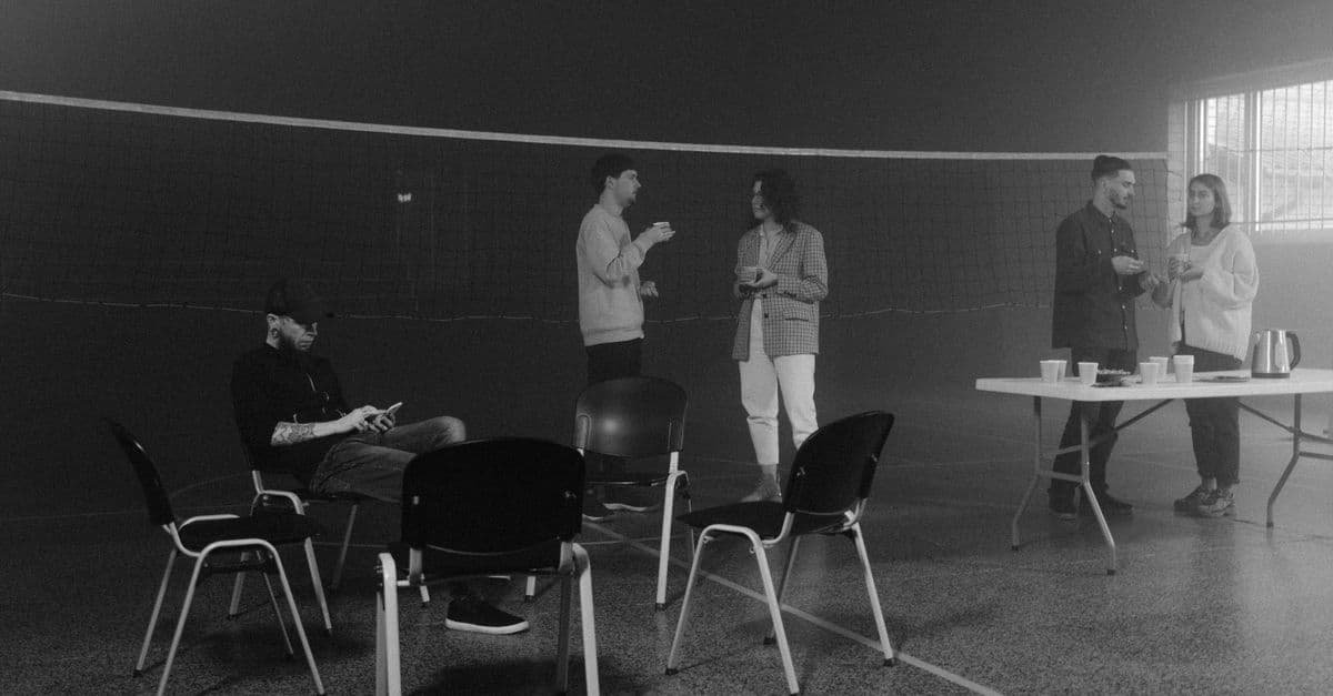A casual indoor gathering with people engaging in conversation and seated arrangement.