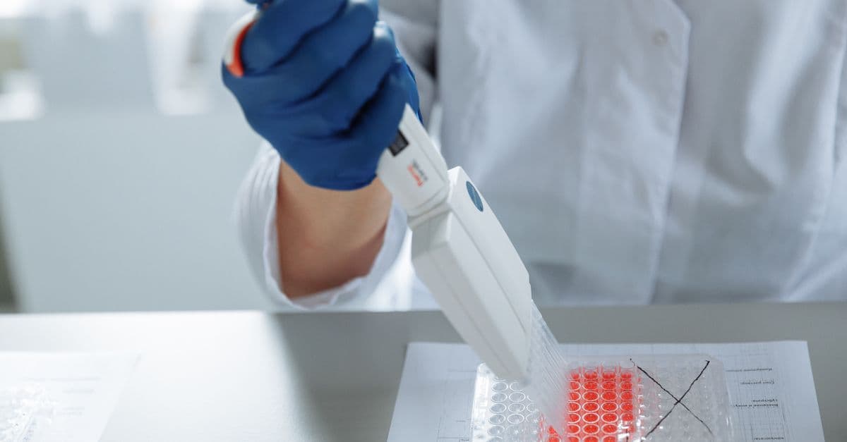 Close-up of a scientist using a pipette in a lab with a focus on sterile procedures.