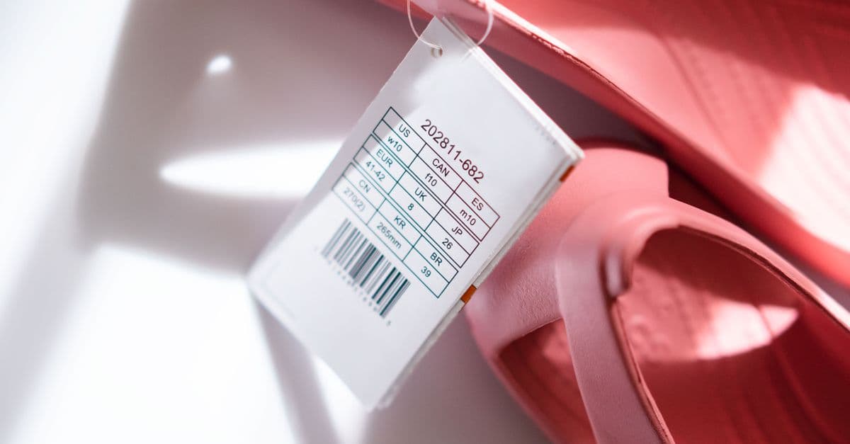 Detailed shot of pink sandals showing size tag and barcode for retail display.
