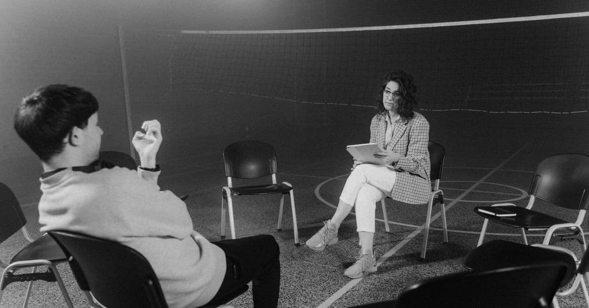 A black and white image capturing a one-on-one counseling session in an indoor setting.