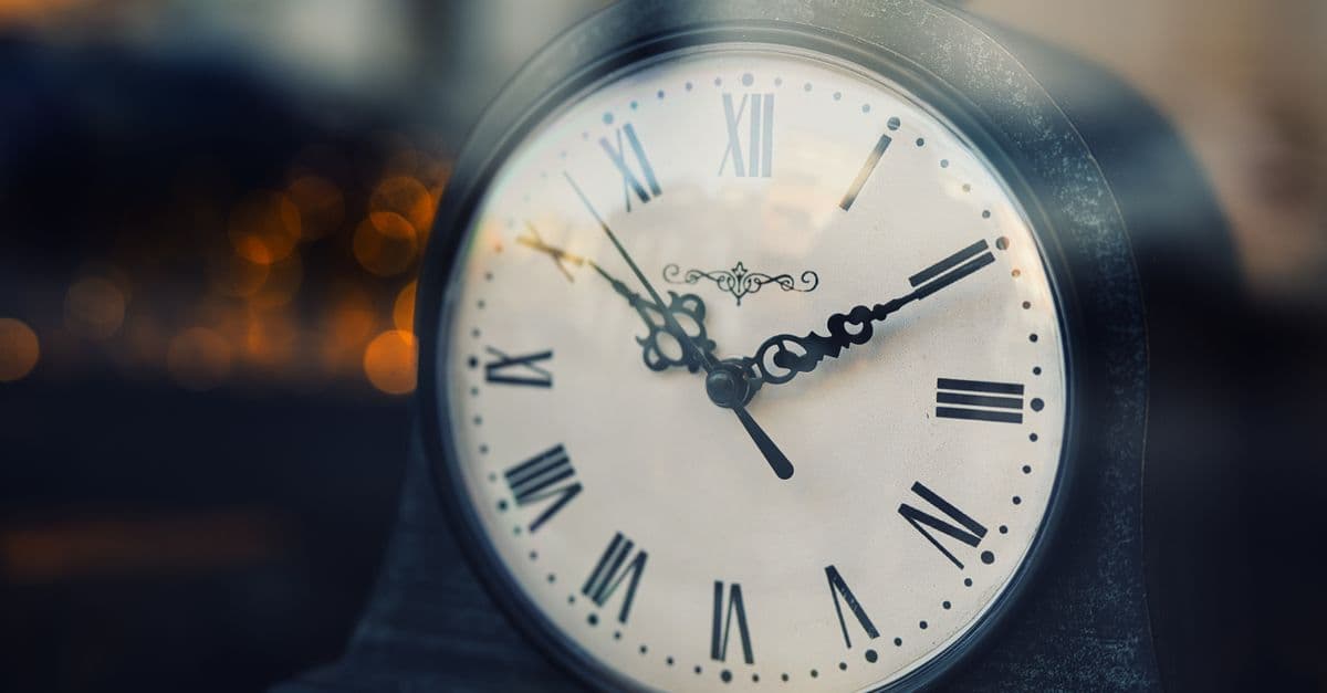 Close-up of a vintage clock with Roman numerals, softly lit background.