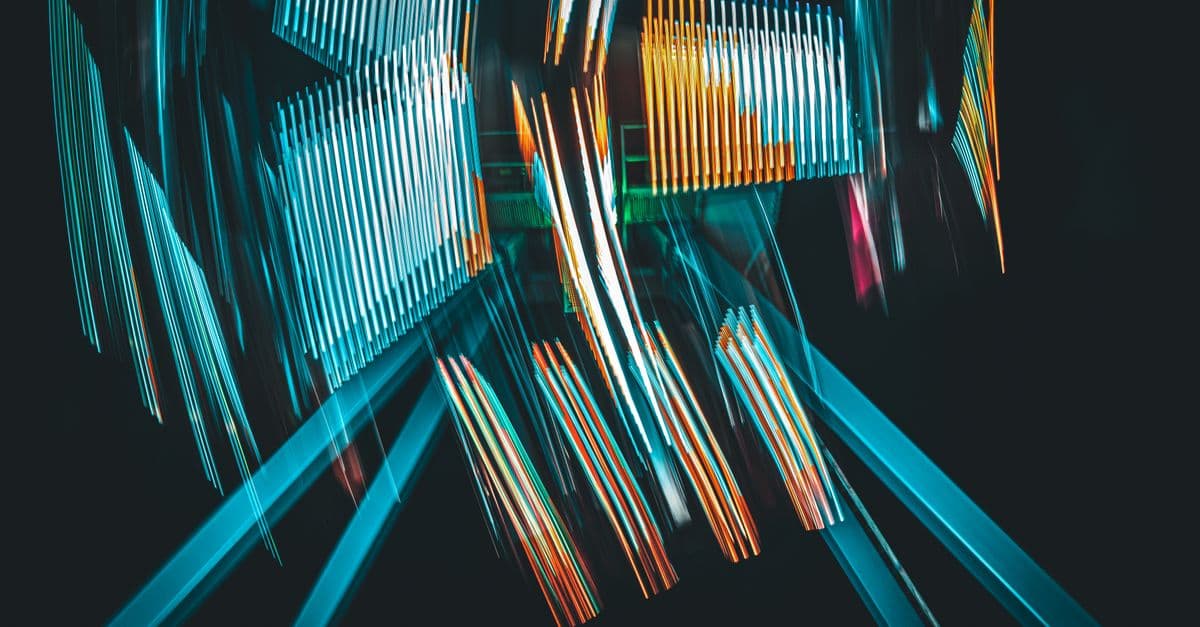 Vivid abstract light trails in motion against a black background, creating colorful geometric shapes.