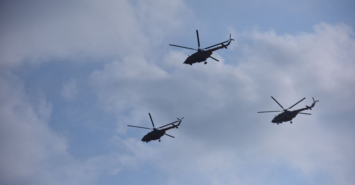 Three helicopters silhouetted against a cloudy sky in an aerial formation, showcasing dynamic aviation.