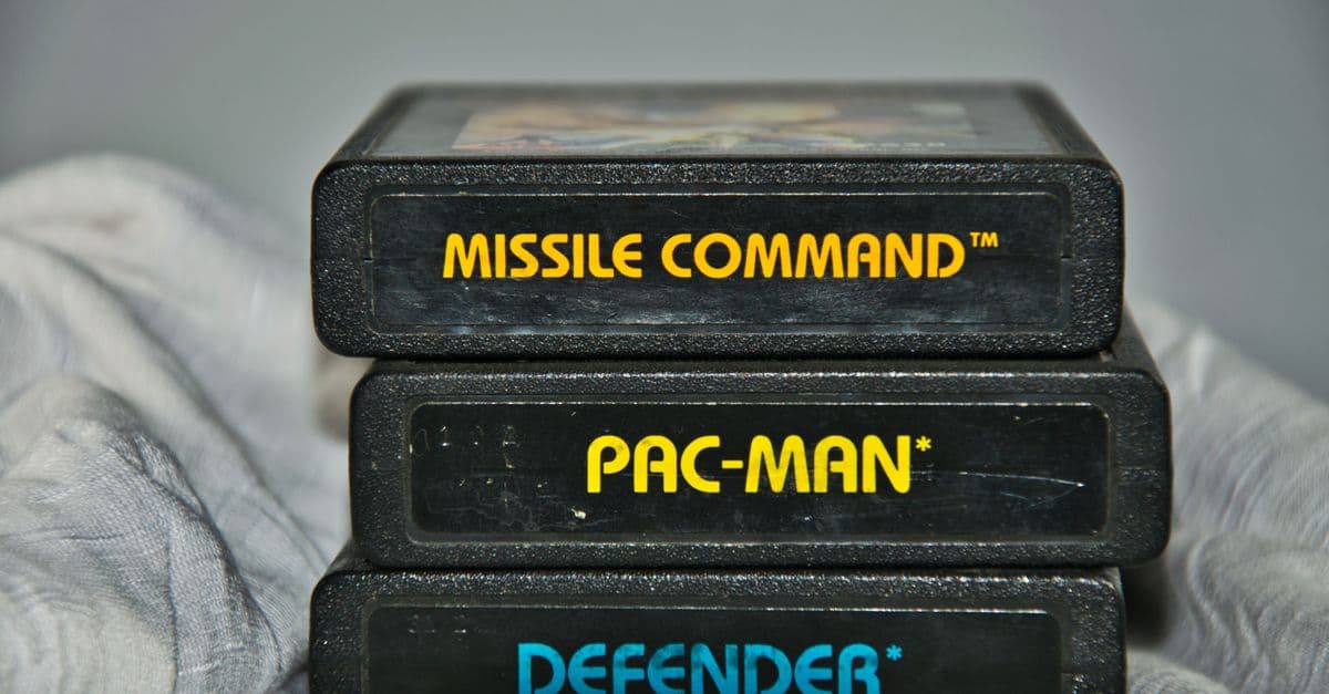 Close-up of vintage Atari game cartridges for Missile Command, Pac-Man, and Defender.