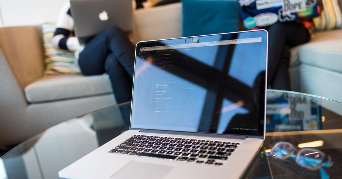 Two people working on laptops in a modern office setting. Technology focus.