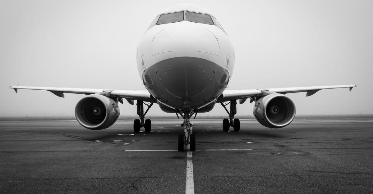A black and white photo of an airplane on a foggy runway, captured head-on. Ideal for aviation themes.
