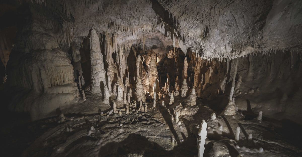 Explore an eerie cave filled with impressive stalactites and stalagmites formations.
