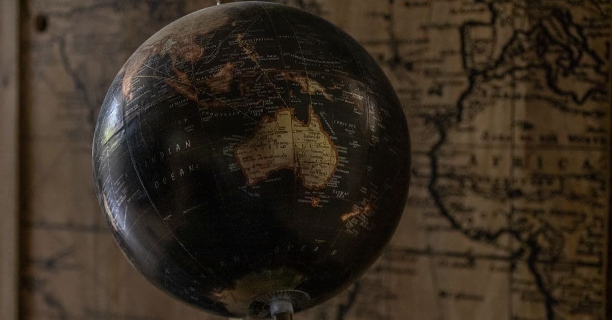 A vintage globe showcases Australia with a sepia world map in the background, offering a classic exploration theme.