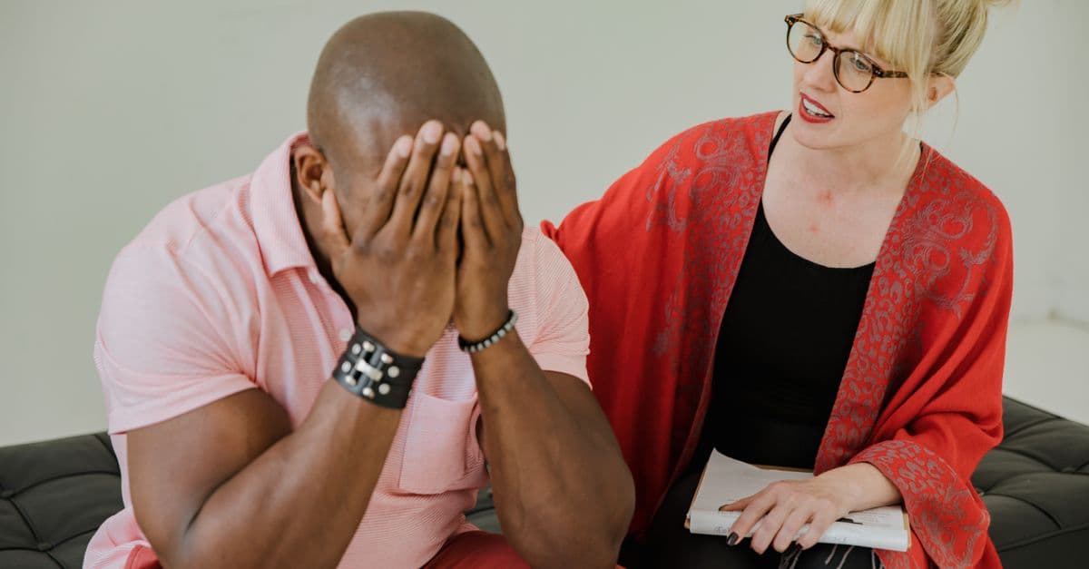 Therapist consoling an emotional client during a therapy session. Indoor setting, intimate atmosphere.