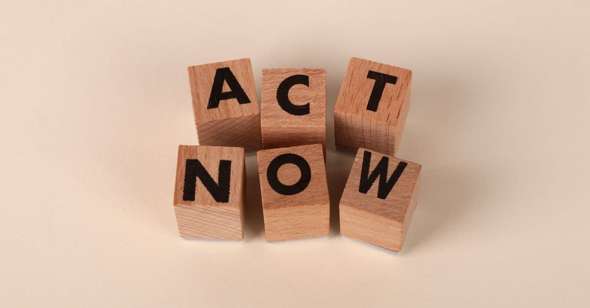 Wooden blocks with letters spelling 'ACT NOW', promoting urgency and motivation.